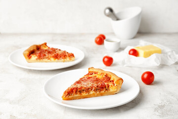 Composition with pieces of tasty Chicago-style pizza and ingredients on light background