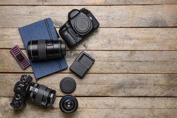 Modern photographer's equipment and notebook on wooden background