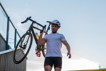 Low angle shot of a sportsman walking down the stairs with his bicycle outdoors