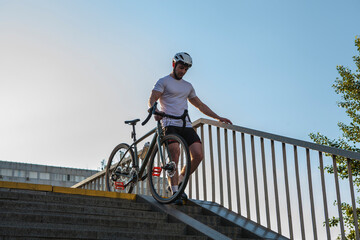 Low angle shot of a sportsman walking down the stairs with his bicycle outdoors