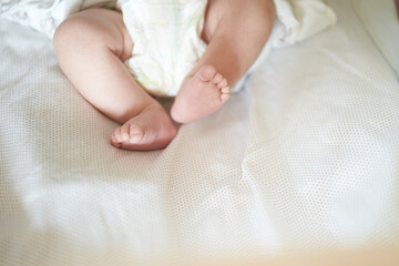 Baby legs on white sheet, newborn baby 1 month, care and love with copy space. High quality photo