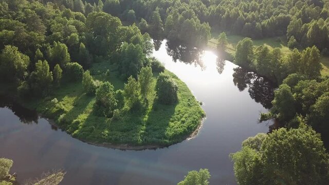 Aerial view of river in green meadows, beautiful sunset light. Meander evening panorama. Oak trees on Svilsoch riverbank. Summer sunny landscape. Picturesque countryside fields. Warm evening, Belarus