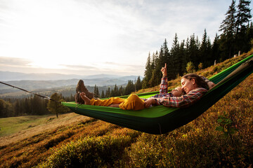 Boy with mom resting in a hammock in the mountains at sunset - 440774917