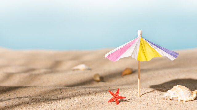  Sunshade umbrella on a sandy beach with seashells. Summer vacation concept.Summer background.