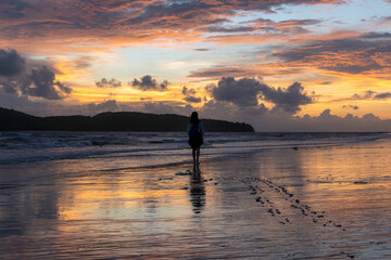 Girl walking on beach at sunset