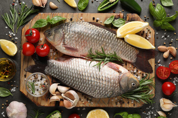 Fresh raw crucian carps and ingredients on grey table, flat lay. River fish