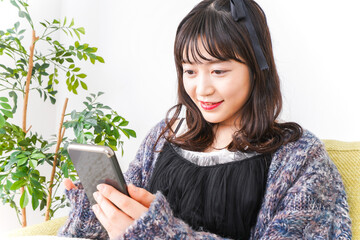 家でスマートフォンを使う若い女性
