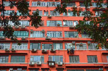 residential high-rise building in red with many air conditioners 