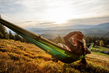 Woman hiker resting after climbing in a hammock at sunset - 440780154