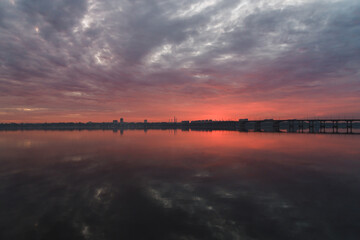 Fototapeta na wymiar Beautiful sunset sky in the city. Sunrise or sunset. Dnepr River. The sky is reflected in a quiet river. Photo from Drona