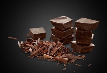 Cocoa powder with chocolate pieces and curls on a dark background.