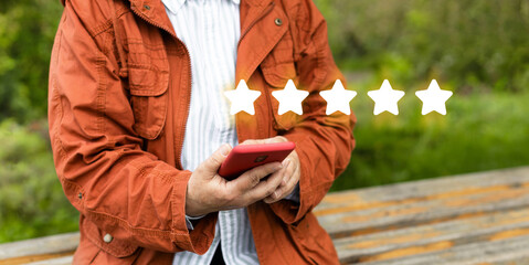 Close up on customer woman hand pressing on smartphone screen with gold five star rating feedback...