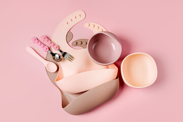 Set of children's tableware and silicone bibs. Baby accessories. Nutrition and feeding concept. Top view, flat lay