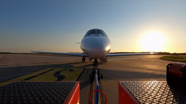 Luxury private jet towed by tow truck on airport taxiway, point of view