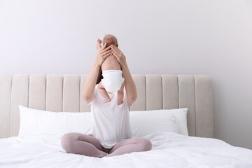 Mom holding her baby in diaper on bed at home - obrazy, fototapety, plakaty
