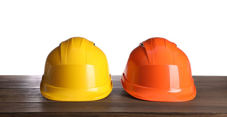 Fototapeta premium Different hard hats on wooden table against white background