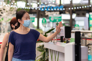 Woman checking body temperature by infrared digital thermometer with his hand.