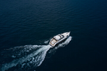 Large boat at high speed on dark blue water and top view. Boats top white waves on dark water. large yacht top view. Aerial view of a boat in motion in dark water.