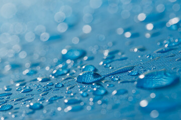 Rain droplets on a blue waterproof fabric  background,close up