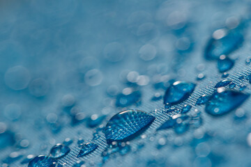 Rain droplets on a blue waterproof fabric  background,close up