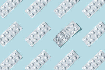 Pills pattern. Composition of medical silver blisters with pills and one used on a blue background. Health care concept. Used packaging from vitamins. Pattern made from blister packs of pills. - obrazy, fototapety, plakaty