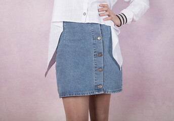 Young fashion woman, with jeans skirt, on pink background.