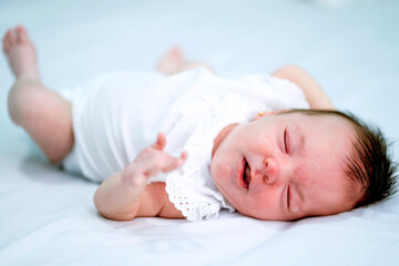 Newborn girl on a bed of white sheets