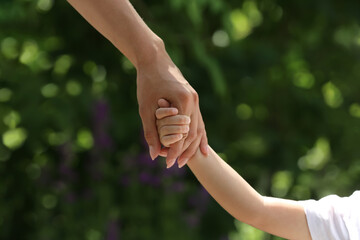 Mom and her child holding hands in park, closeup