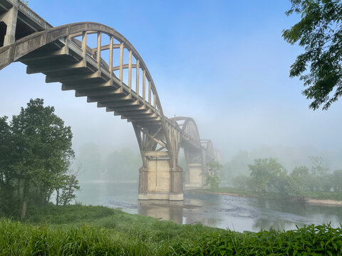 Rainbow bridge in fog over the famous White River in Cotter, Arkansas, Trout Capital of the World - Historic Ruthven Rainbow Arch Bridge