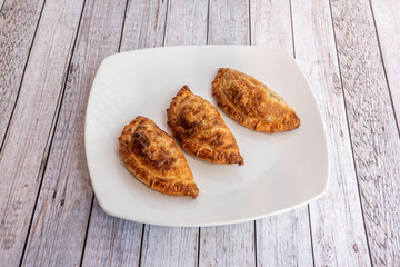 Argentine empanadas stuffed with veal with puff pastry on white plate