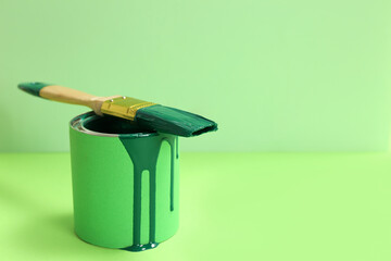 Can of green paint with brush on color background. Space for text