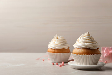 Delicious cupcakes decorated with cream on light grey table. Space for text