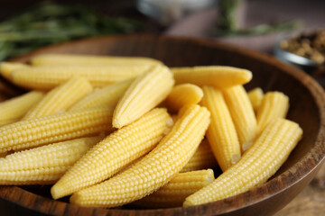 Fresh baby corn cobs in wooden bowl, closeup