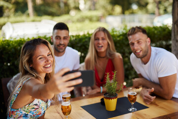 Group of young people having fun in a sumemer bar and taking selfie