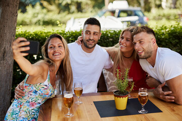 Group of young people having fun in a sumemer bar and taking selfie