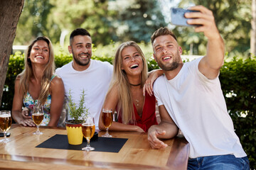 Group of young people having fun in a sumemer bar and taking selfie