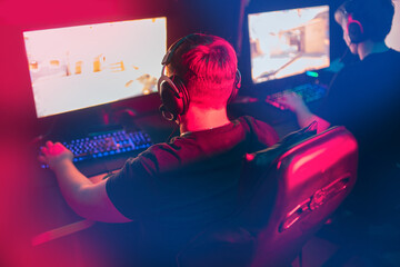 Blurred background professional gamer playing championship online games computer with headphones,...