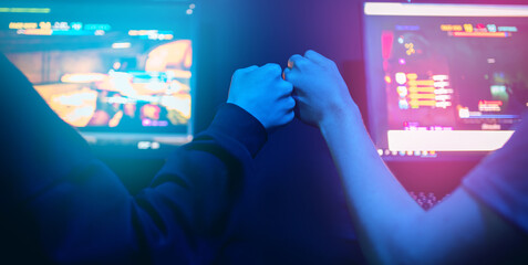 Gamers support team fists hands online game in neon color blur background. Back view soft focus
