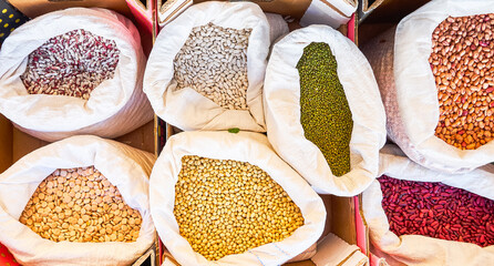 Different types of beans of various colors and lupins in sacks for sale in bulk at a local flea market