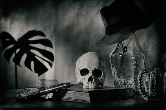 still life imitate wet plate photography style focus Skull on a large old book and a large glass bottle with a cross necklace and fedora Gangster with guns