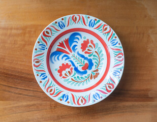 Vintage colorful painted porcelain plate on a wooden background