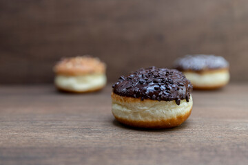 Delicious glazed chocolate donuts on wooden background