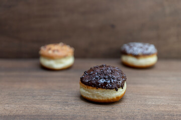 Delicious glazed chocolate donuts on wooden background