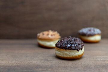 Delicious glazed chocolate donuts on wooden background