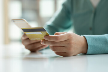 Close up woman hand using credit card and smartphone laptop for buying online shopping