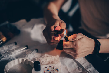 Male hands refill printer cartridge. The guy makes holes in the cartridge and pours ink through the...