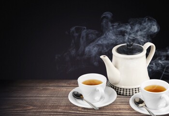 Aromatic herbal hot tea in glass teacup on wooden desk.