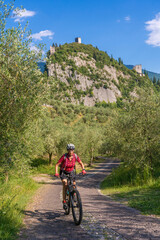 nice and active senior woman riding her electric mountain bike in the Garda lake mountains between...