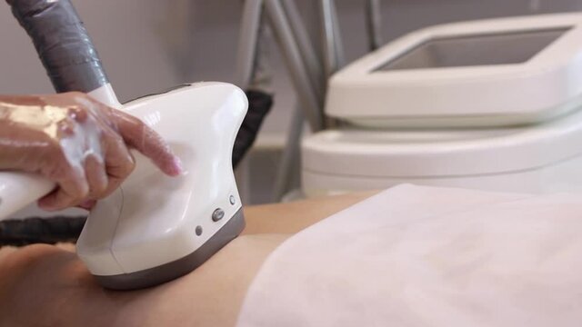 Hardware anti-cellulite massage. RF lifting procedure. The beautician guides the device along the client's leg. Ultrasound cavitation body contouring treatment. Anti-fat therapy.
