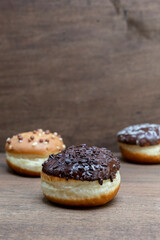 Delicious glazed chocolate donuts on wooden background
